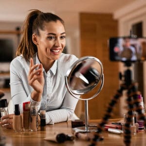 Smiling female influencer talking about beauty products while vlogging from home. Learn how influencers working